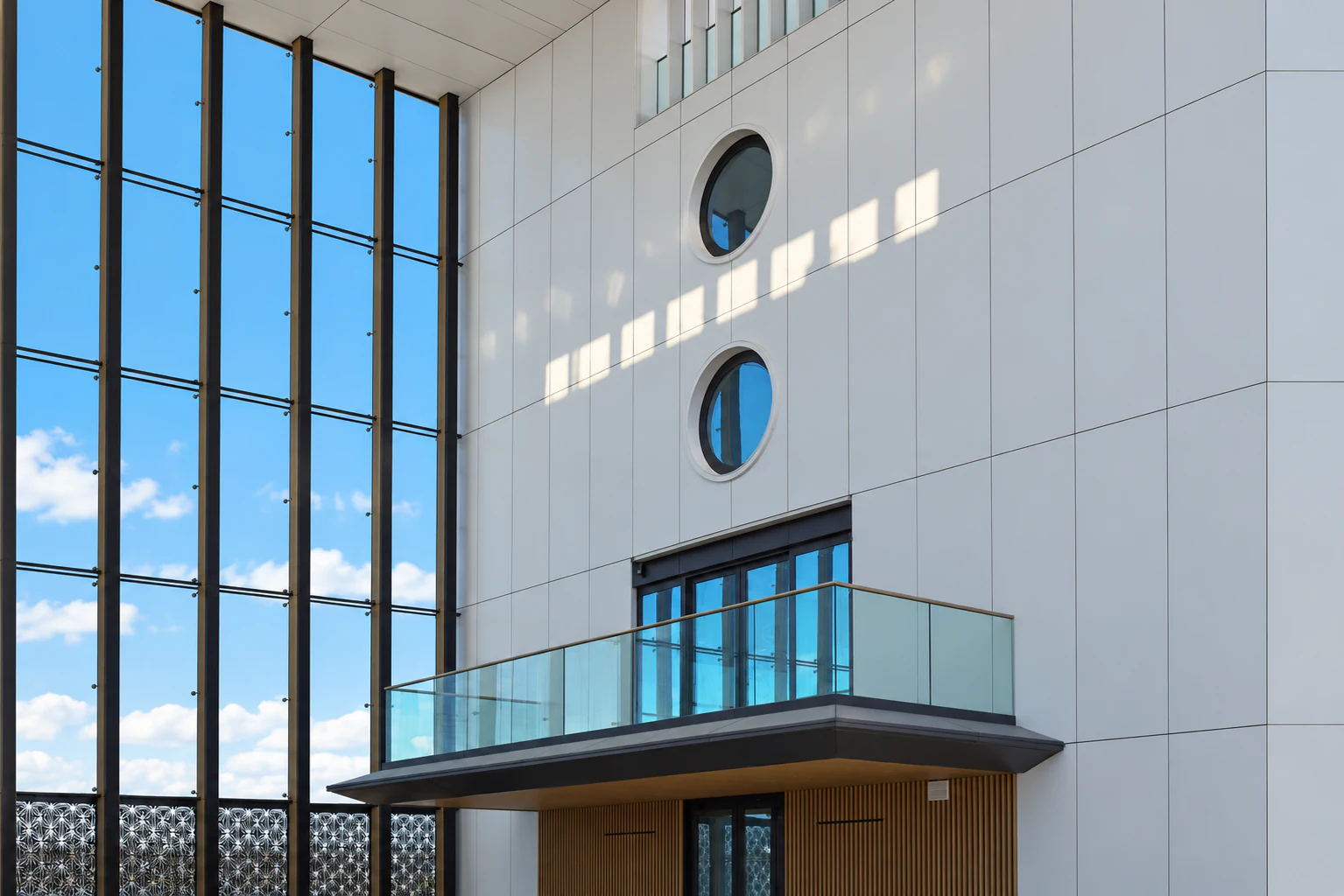 Courtyard between the villas with glass wind screen, circular opening windows and balcony