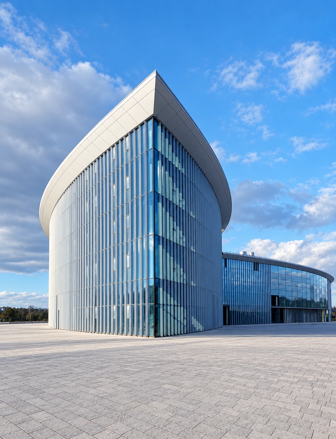 Curved glass building with slender vertical metal profiles and a continuous projecting roof